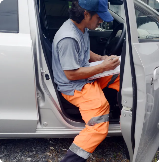 作業ズボンを履いたスタッフが車から降りる場面